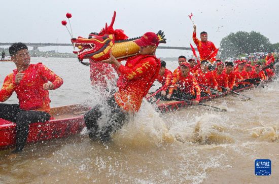 6月22日，在湖南省岳阳市湘阴县湘江临资口水域，参加龙舟赛的队员接“龙头”下水。