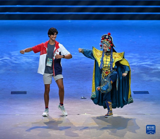 7月29日，美国运动员杜恩（左）在联欢会现场与川剧演员互动。新华社记者 蔡湘鑫 摄