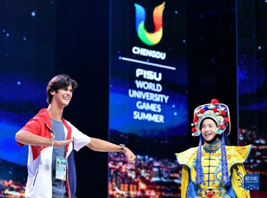 7月29日，美国运动员杜恩（左）在联欢会现场与川剧演员互动。新华社记者 张端 摄