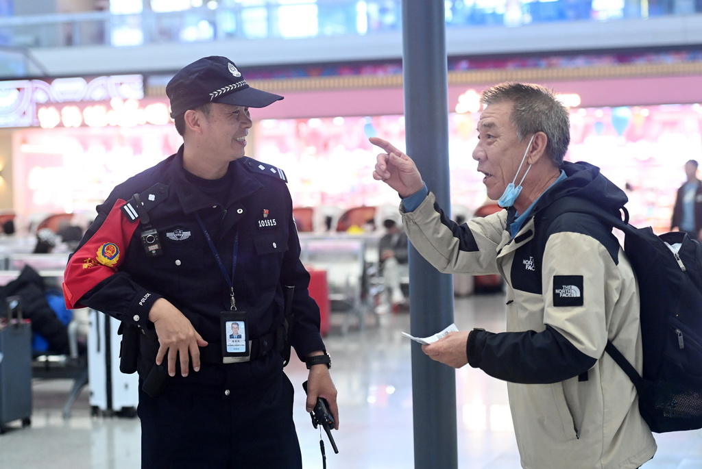 1月8日，高明伟（左）在南宁东站向旅客解答问题。